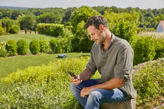 A man sitting in the garden and using his smartphone